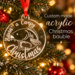 A Carpy Christmas custom made acrylic fishing bauble displayed on a festive tree